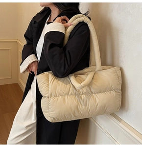 Detail of a large beige quilted puffer tote bag shown on model with soft lighting