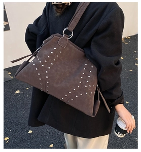 Detail of dark brown suede tote bag with silver studs and circular metal hardware