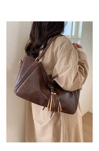 Detail of dark brown tote bag featuring handmade woven edges and large leather tassel