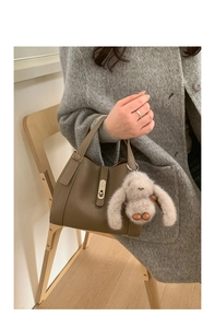 Detail of a brown lychee pattern bucket bag with a cute plush bunny pendant