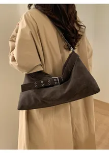 Detail of dark brown suede shoulder bag featuring vintage buckle and metal eyelet design
