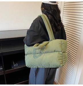 Detail of avocado green quilted puffer tote bag showing padded straps and soft texture