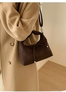 Detail of dark brown suede shoulder bag with leather knot and silver metal rivets