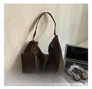 Détail du sac cabas en daim marron foncé avec pochette assortie et ordinateur pour le travail