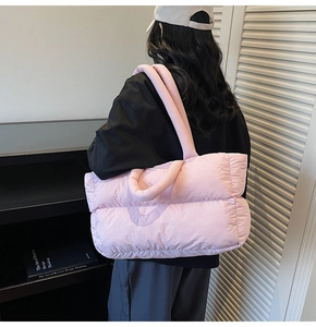 Detail of pink puffer tote bag with quilted padding and soft shoulder strap on a model