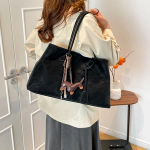 Detail einer schwarzen großen Tote Bag mit Dackel-Anhänger und gewebtem Quasten-Detail