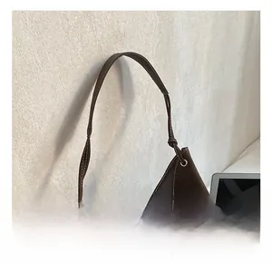 Détail du sac à bandoulière en daim marron foncé avec surpiqûres blanches contrastées