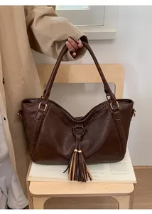 Detail of vintage brown leather tote bag with braided side seams and stylish tassels