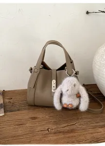 Detail of vintage khaki crossbody bag with litchi texture and cute rabbit charm