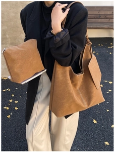 Detail of vintage brown matte leather tote bag and matching pouch with white stitching