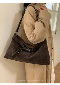 Detailed close-up of dark brown suede tote bag with retro metal buckle and eyelet strap