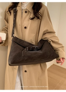 Close-up of dark brown suede shoulder bag showing metal buckle detail and matte texture