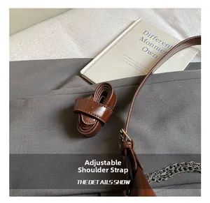 Λεπτομέρεια ρυθμιζόμενου καφέ δερμάτινου ιμάντα με ασημένια αγκράφα και αλυσίδα τσάντας