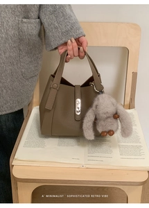 Detail view of lychee pattern leather bucket bag with silver lock and rabbit charm