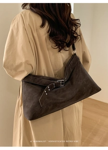 Close-up of a large vintage brown suede tote bag with a decorative silver belt buckle detail