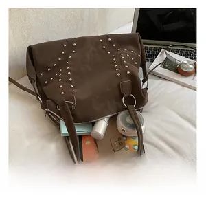 Interior storage detail of the studded brown tote bag with daily items and tablet
