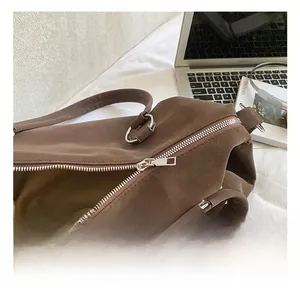 Detail of high-quality silver metal zipper and D-ring on dark brown textured tote bag