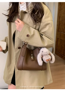 Close-up of brown lychee texture leather handbag with a plush white bunny charm