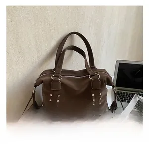 Detail showing silver rivets on brown suede tote bag with metal ring handles and zipper