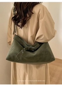 Detail of dark olive green suede tote bag with silver buckle strap and matte texture