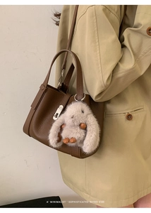 Detail of brown litchi pattern leather handbag with cute white plush rabbit charm