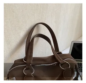 Detail of dark brown tote bag featuring sturdy handles and silver metal ring hardware