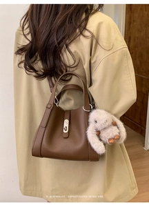 Detail of retro dark brown leather bag with silver lock and plush bunny pendant