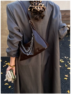 Détail du sac d'épaule en cuir verni marron foncé avec chaîne argentée et fini brillant