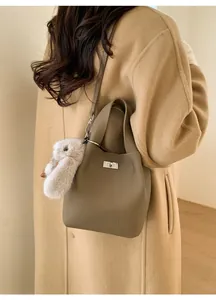 Detail of lychee pattern leather bucket bag with silver lock and plush rabbit pendant