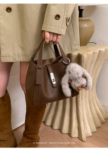 Detail of dark brown leather handbag with silver lock and plush rabbit charm