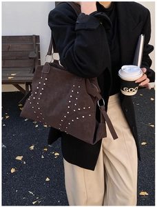 Detail of dark brown suede tote with silver rivets in a stylish urban lifestyle setting