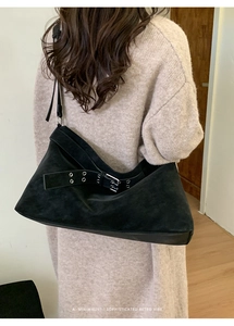 Detailed back view of a large black suede tote bag with metal eyelet strap on a model