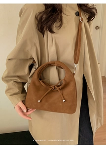 Close-up of minimalist retro brown crescent bag with bow detail worn as crossbody