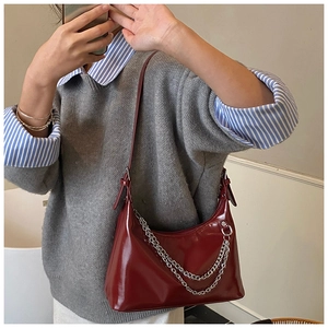 Détail du sac bandoulière rouge foncé brillant avec chaîne argentée et design épuré