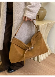 Close-up of vintage brown tote bag with metal buckle detail in a minimalist setting