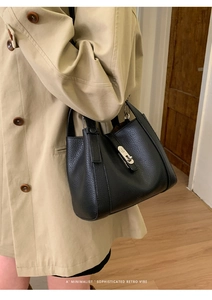 Detail of silver twist-lock closure on a black pebbled leather crossbody handbag