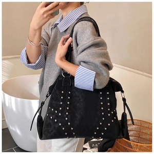 Detail of black suede tote bag with decorative silver metal studs in triangle pattern