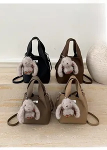 Detailed view of four textured leather bucket bags with plush rabbit charms and straps
