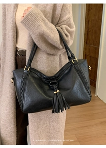 Close-up of black retro tote bag featuring stylish tassel detail and braided side stitching