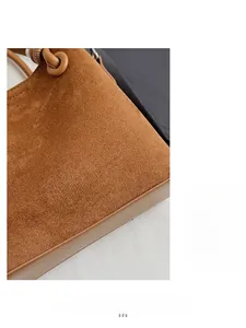 Detailed close-up of brown suede fabric texture and silver logo on minimalist handbag