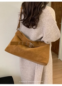 Detail of caramel brown suede tote bag featuring a large decorative metal buckle and strap