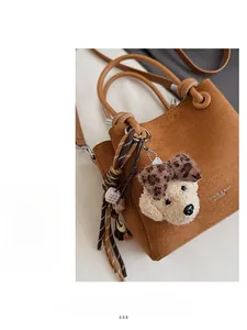 Macro detail of brown suede bucket bag featuring a plush puppy charm and leopard bow