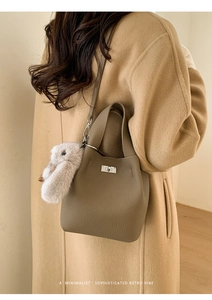 Close-up of brown pebbled leather bucket bag with silver twist lock and bunny charm