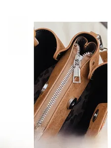 Detail of brown suede bucket bag with leopard print lining and magnetic snap closures