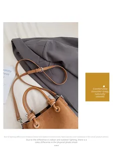 Detail of a brown suede small square bag with round handle and metal hardware