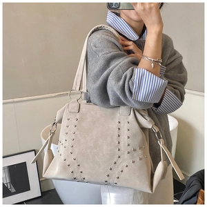 Detail view of khaki suede tote bag featuring symmetric metal studs and wide shoulder strap