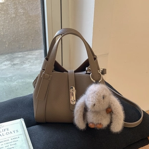 Detailed close-up of taupe litchi leather bucket bag with silver twist lock and bunny charm