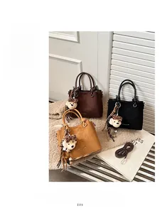 Detail of matte frosted bucket bags in brown and black with plush bear charms
