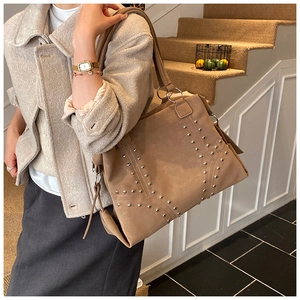 Détail du sac hobo kaki avec rivets argentés et texture en daim vintage sur un modèle