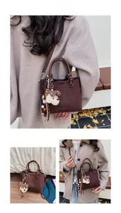 Detail of dark brown suede bucket bag with plush puppy pendant and beaded tassel charm